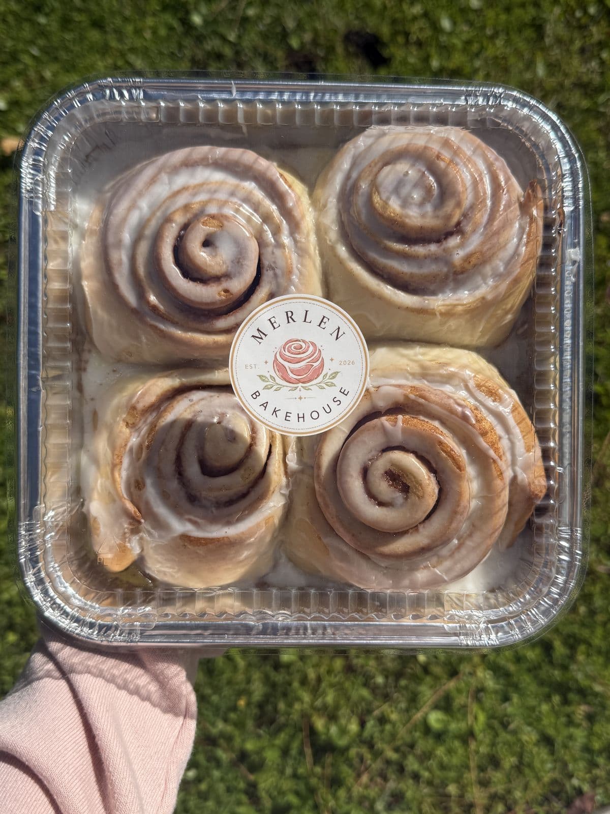 A box of four Merlen Bakehouse cinnamon rolls on the grass