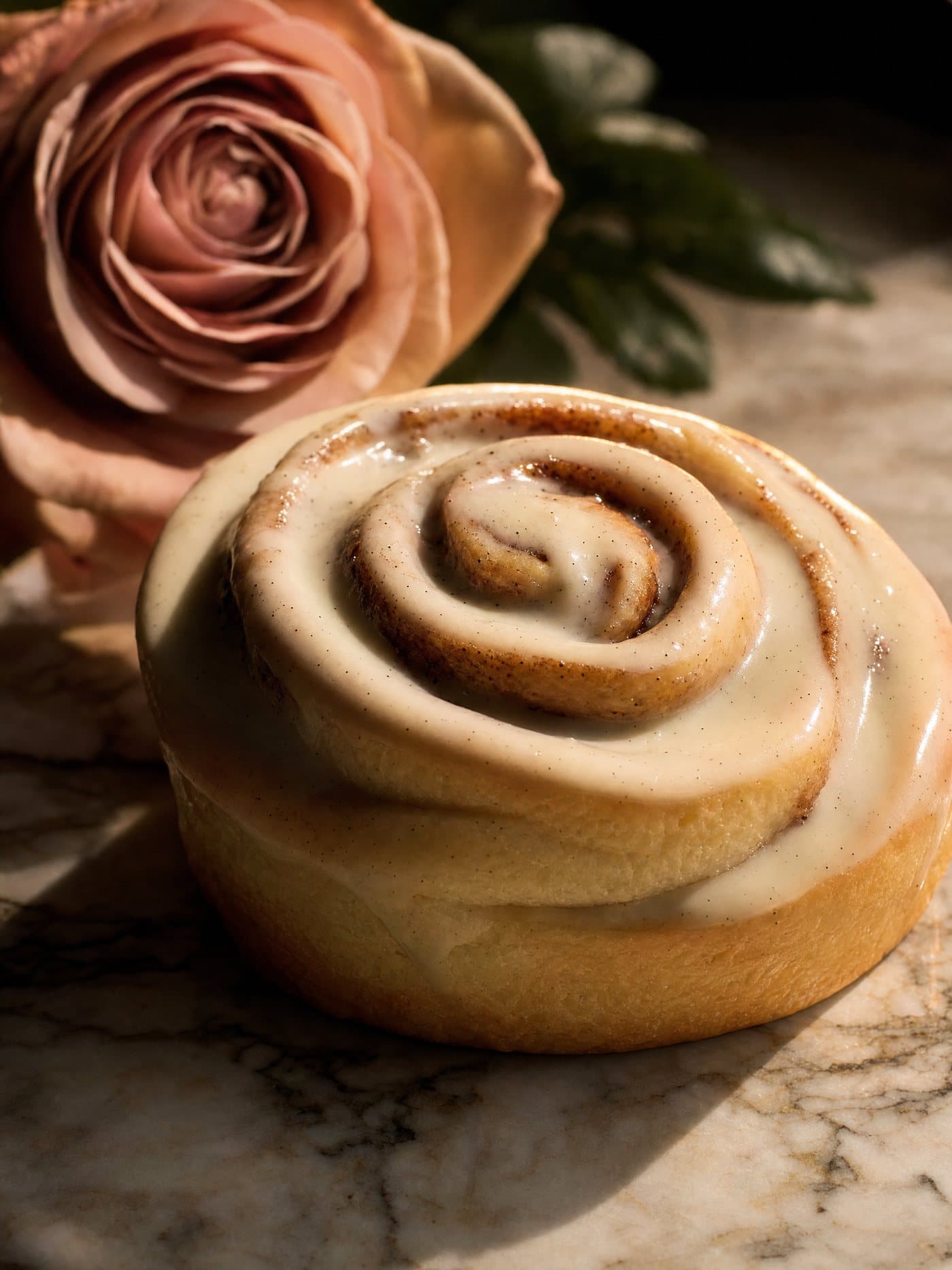 A plated Merlen Bakehouse cinnamon roll with rose petals